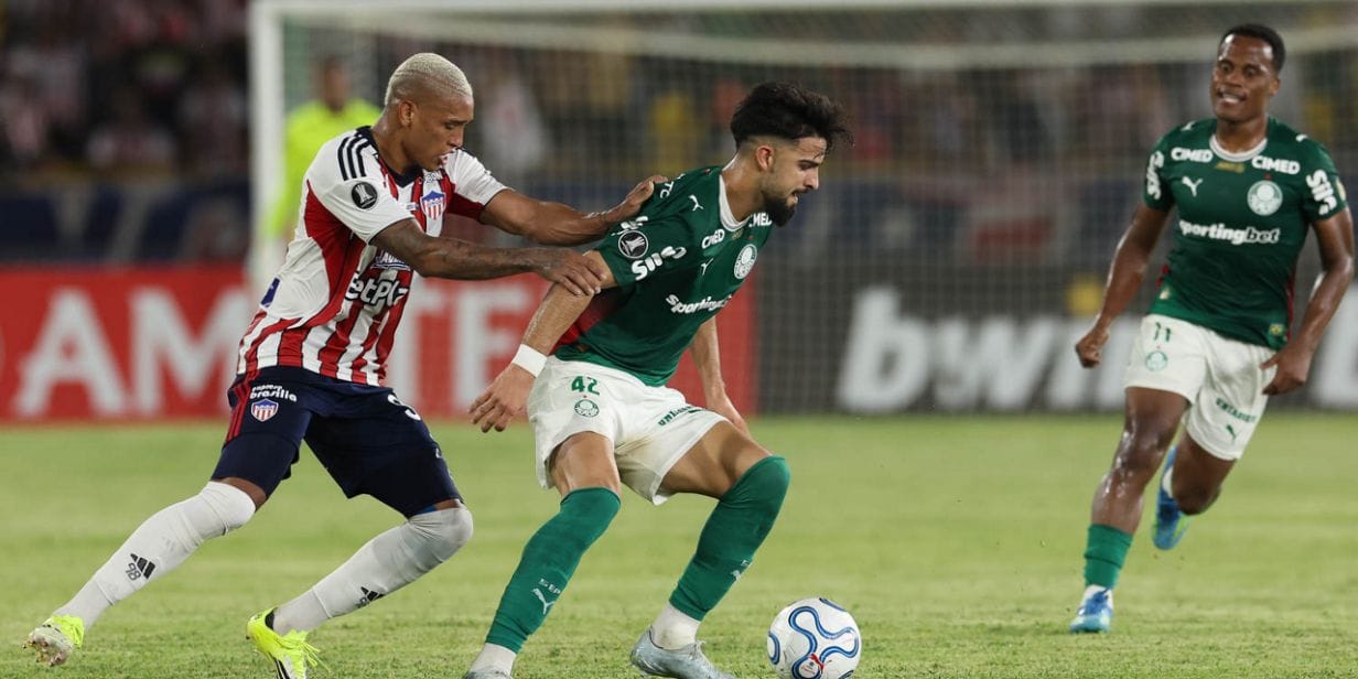 Flaco López (centro), do Palmeiras, tenta passar pela marcação do Junior Barranquilla, em jogo da Libertadores - Cesar Greco/Palmeiras